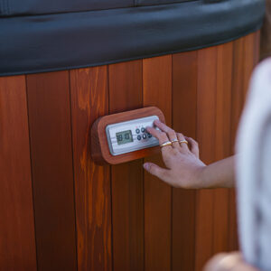 Close up of hand using Moji Hot Tub control panel on Cedar wood panels demonstrating ease of use